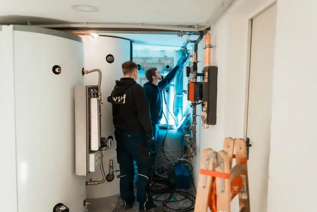 Zwei ws+f Mitarbeiter arbeiten gemeinsam an der Haustechnik in einem Technikraum