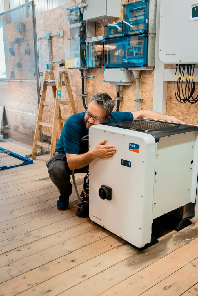 Ein Mitarbeiter installiert ein Batteriespeichersystem in einem Technikraum.